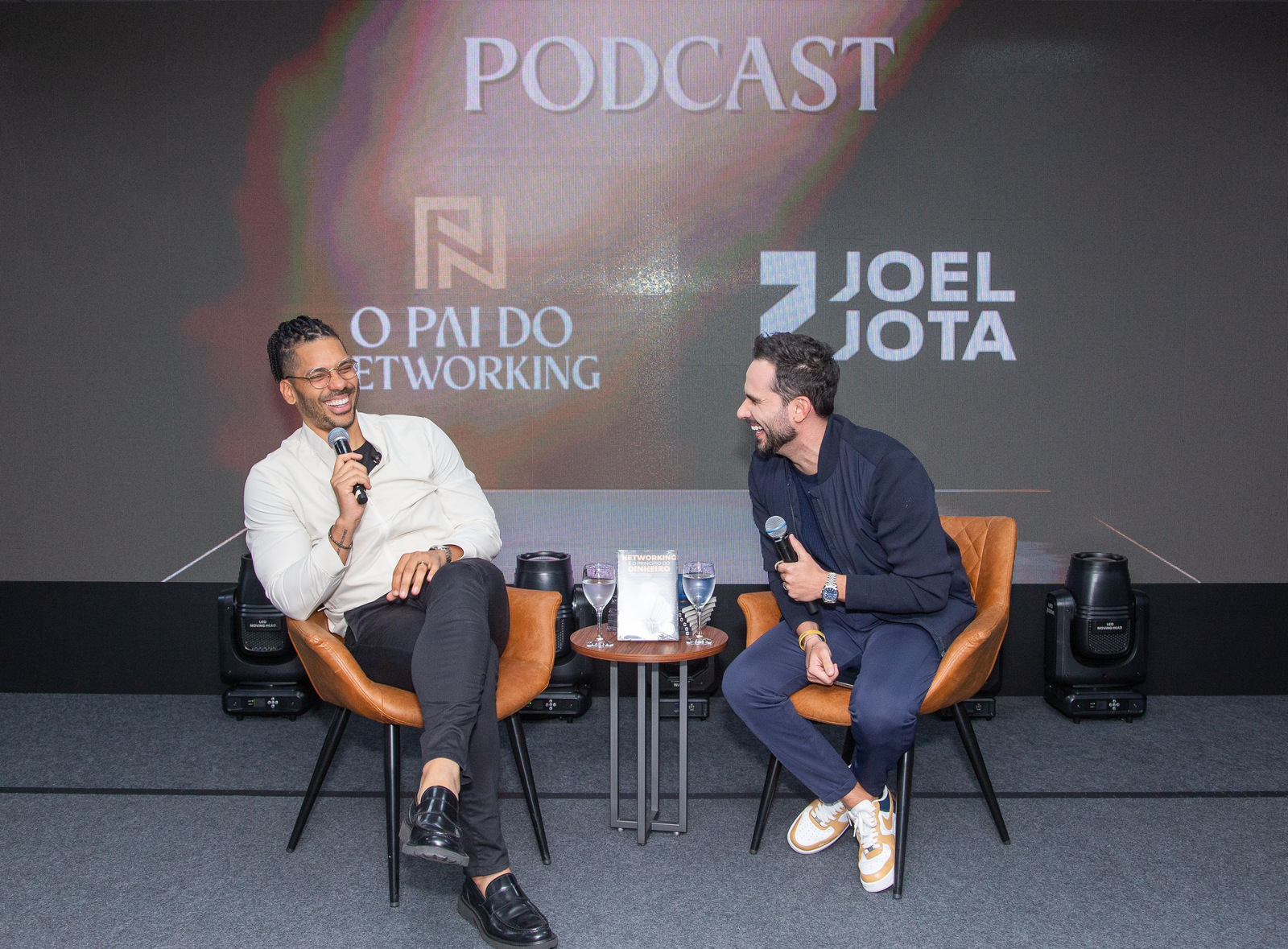 Daniel Gramigna e Joel Jota em conversa no palco, com o livro sobre a mesa